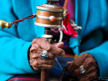 Praying wheel in hands of old tibetian woman, Nepal